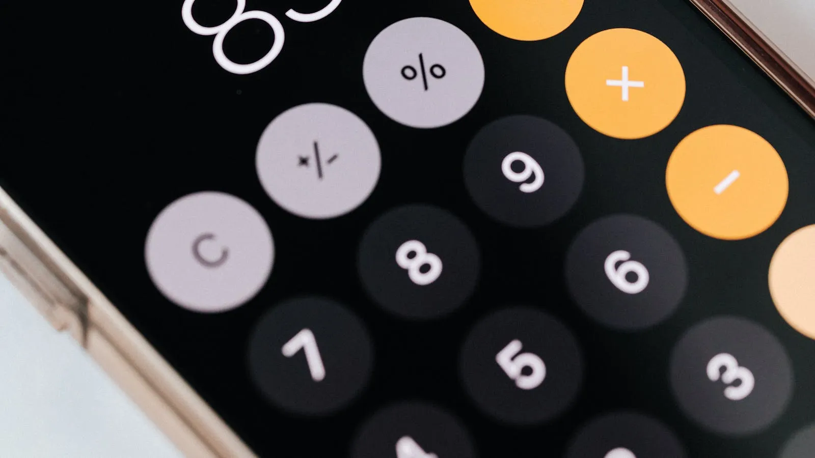 Close-up of a smartphone calculator app with orange and white buttons, representing the monthly Tourism Dirham calculation
